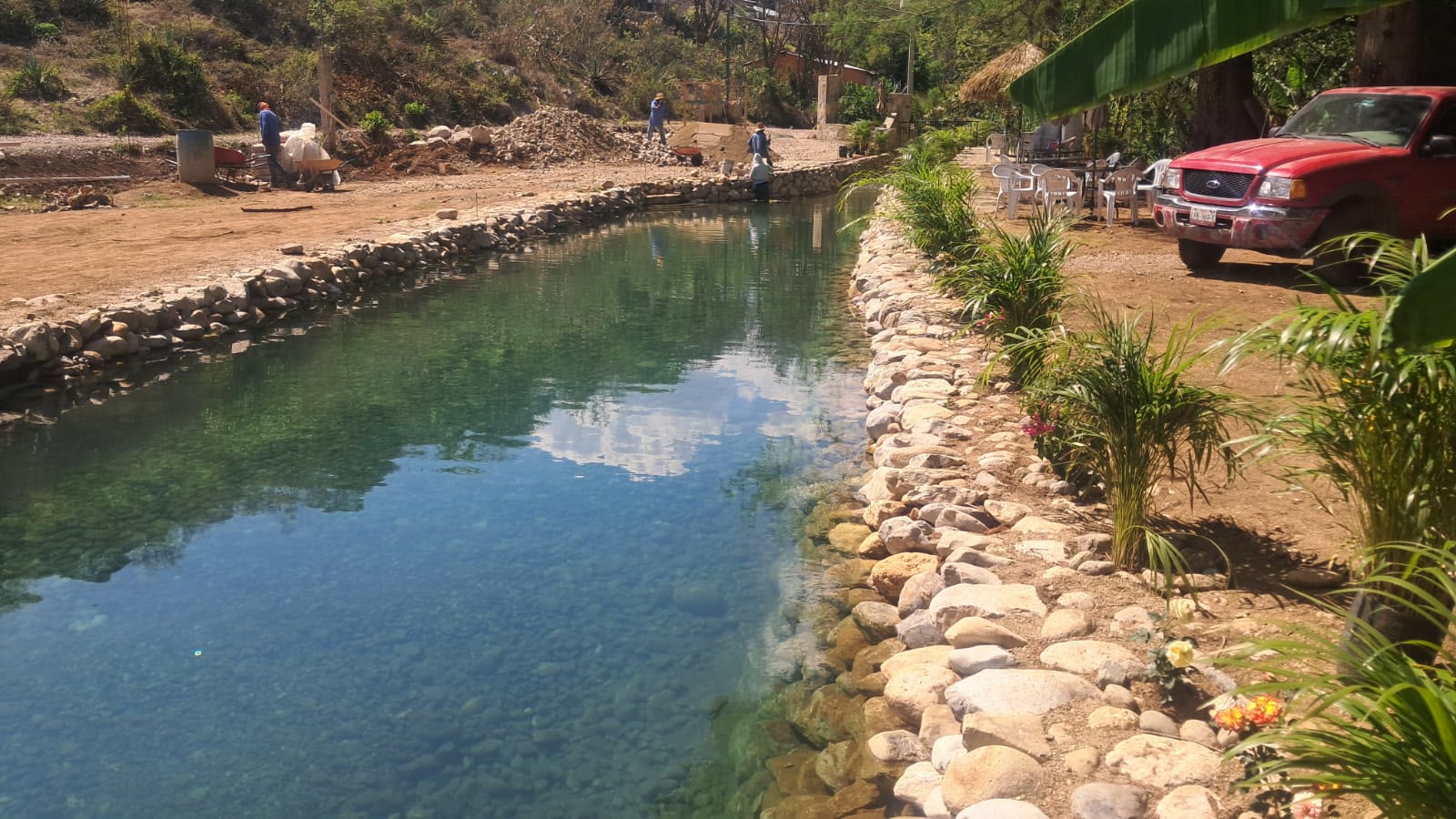 Alberca larga de piedra con el reflejo de las montañas en el agua